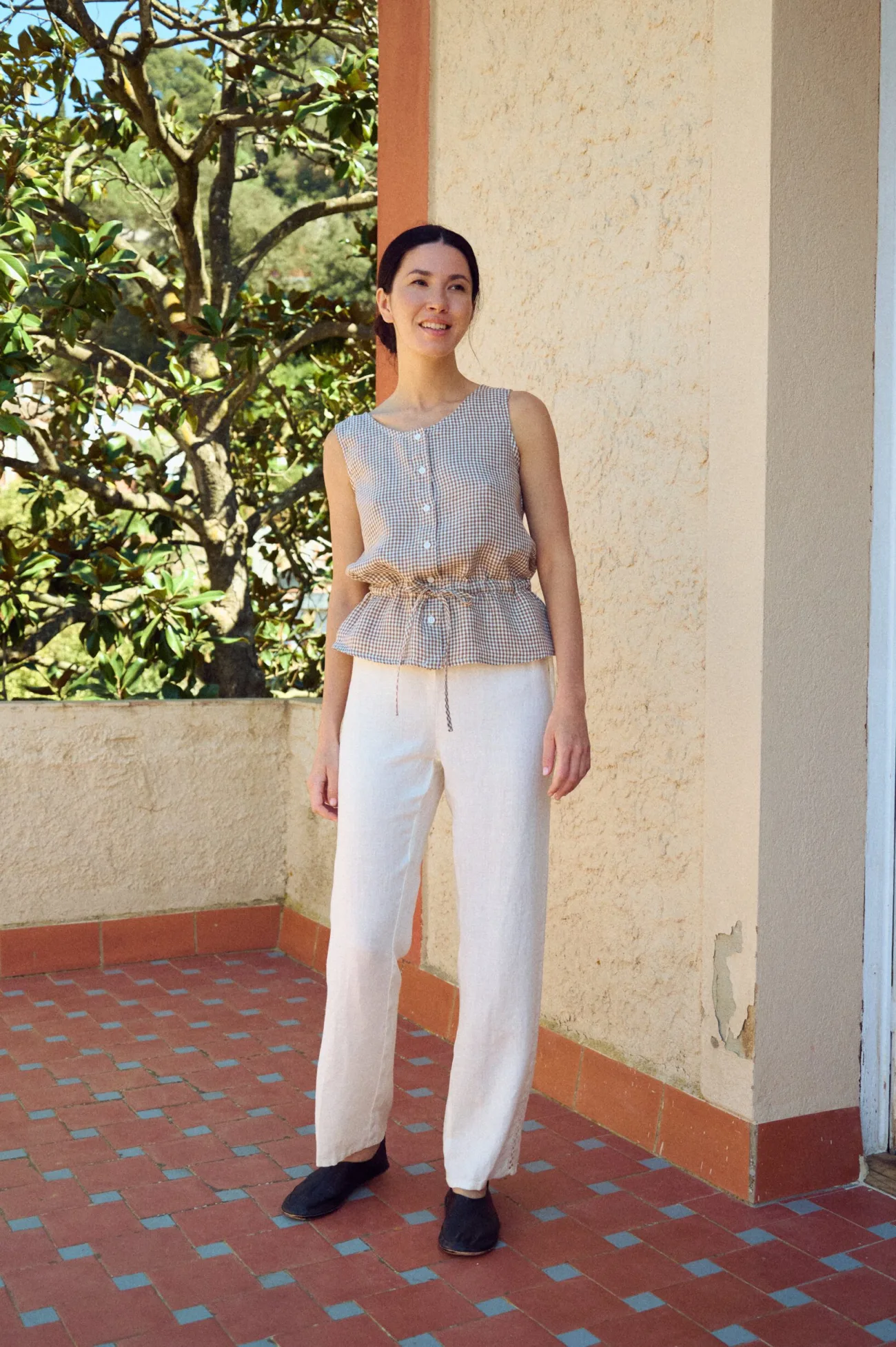 model wearing linen drawstring pants in white with lace details and peplum gingham top