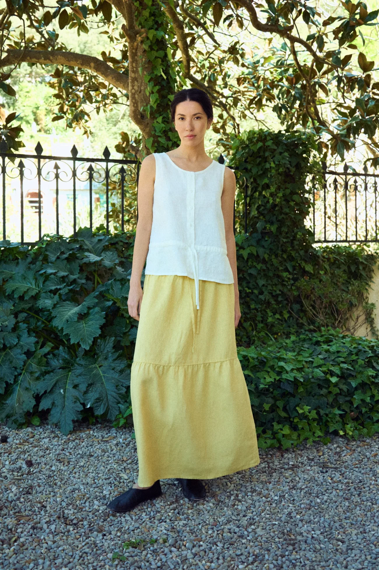 model wearing white linen sleeveless blouse styled with butter yellow tiered linen skirt