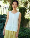 White sleeveless linen top with a relaxed fit, round neckline, button-front closure, and subtle waist seam with tie detail