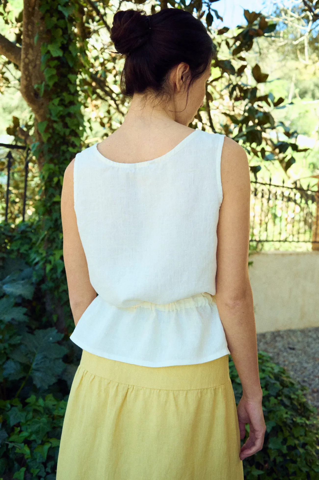 the back of sleeveless linen peplum blouse in white