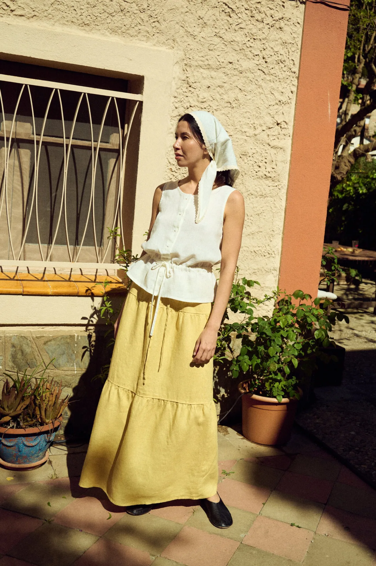 woman wearing white linen bandana with lace trim styled with tiered butter skirt and white sleeveless top