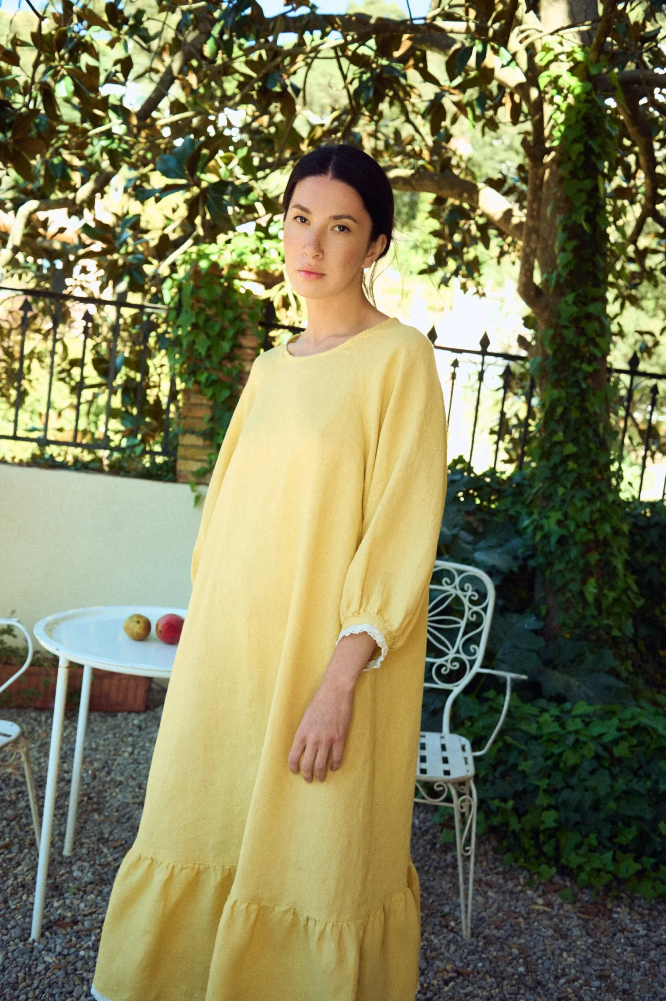 Loose yellow linen dress with an easy A-line shape, round neck, softly gathered three-quarter sleeves with lace-trimmed cuffs