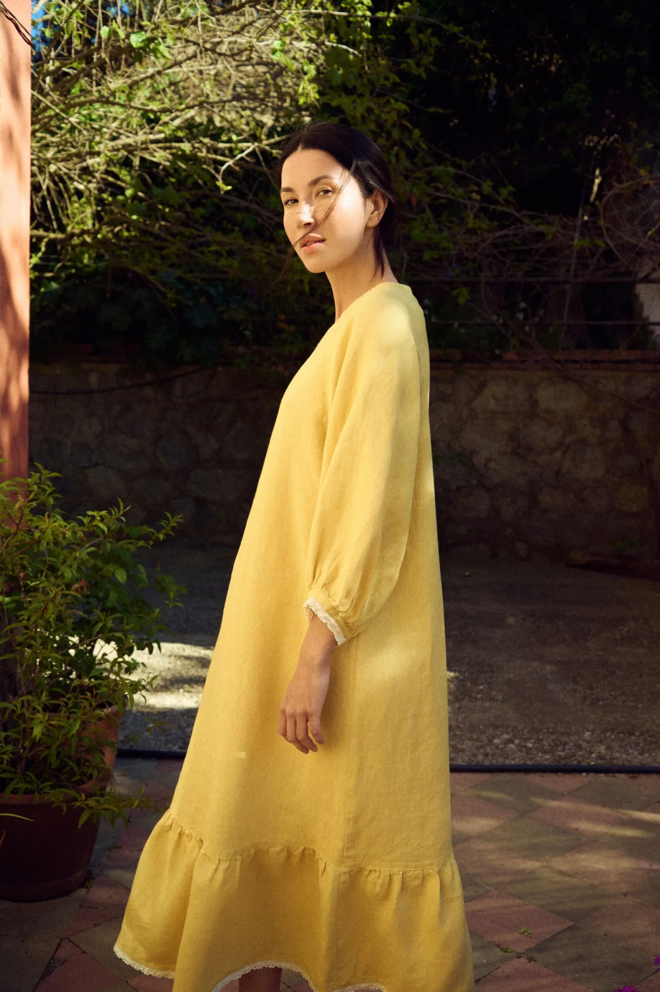 Soft yellow linen dress with a loose A-line silhouette, round neckline, and three-quarter sleeves gathered into delicate lace-trimmed cuffs