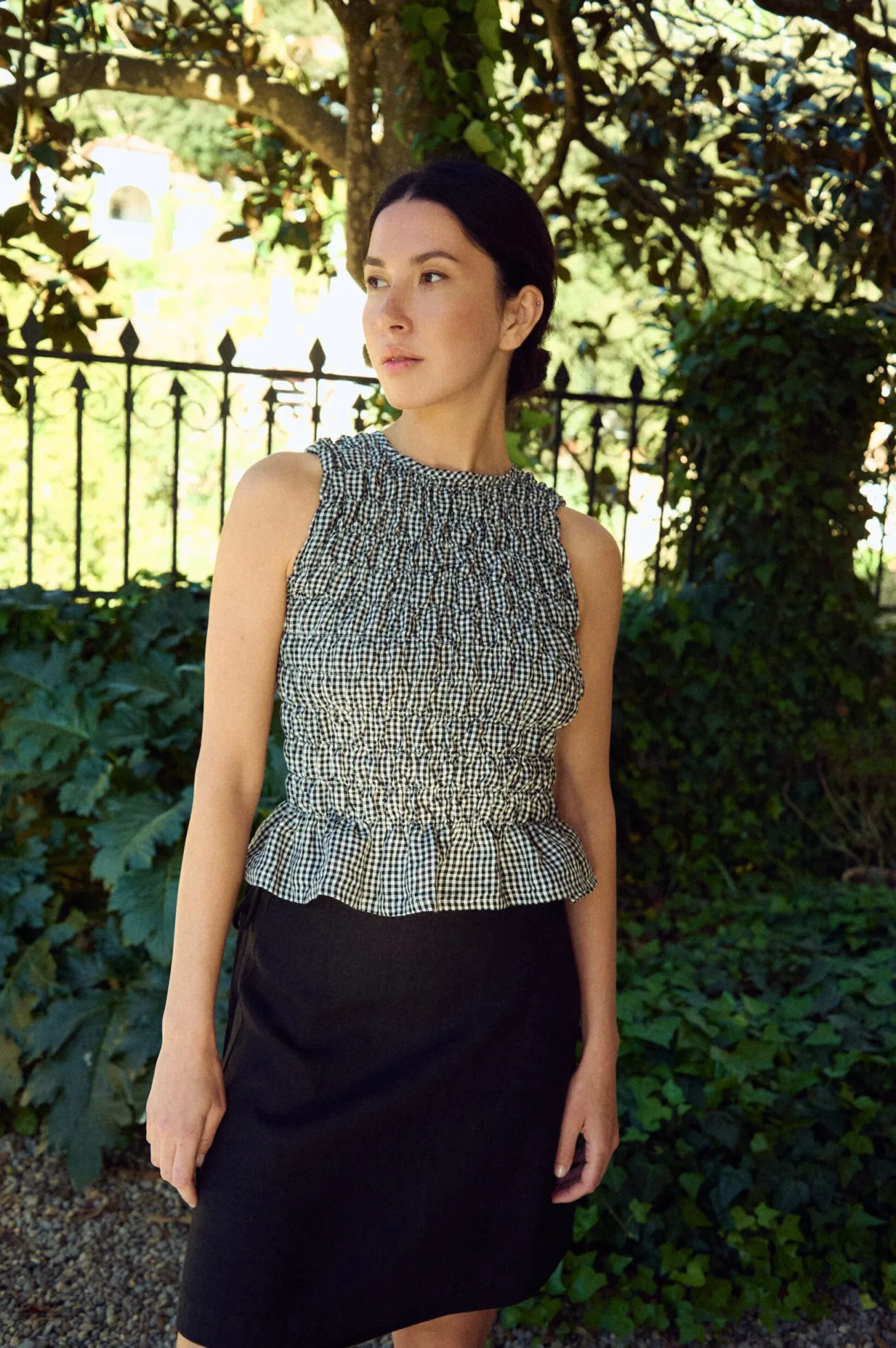 woman wearing black gingham smocked peplum linen top styled with mini black skirt