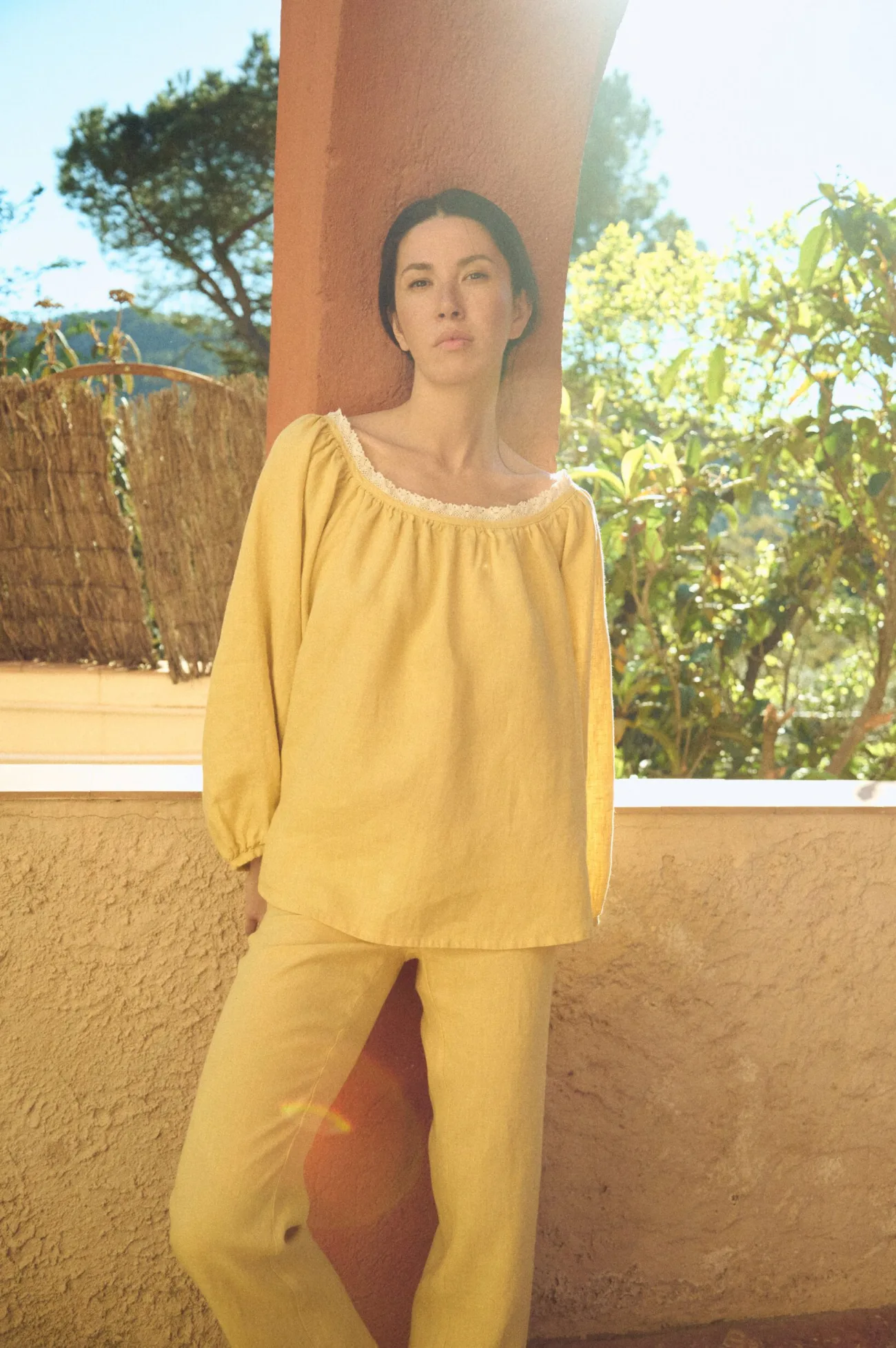 Front view of yellow linen blouse with lace-trimmed scoop neckline, gentle gathers, and softly billowed sleeves