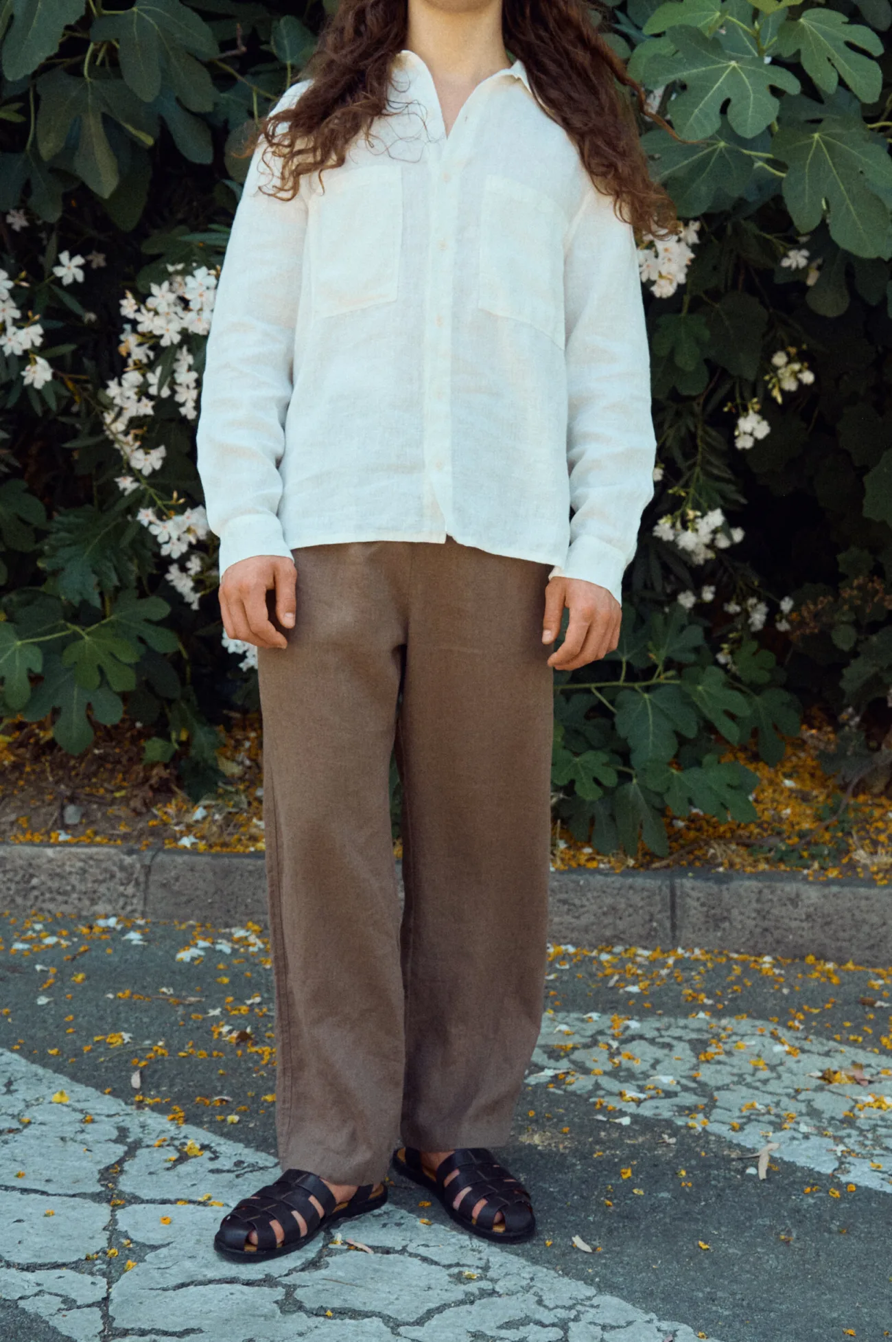 Men’s brown linen trousers with a relaxed wide leg, styled with a milky white linen shirt