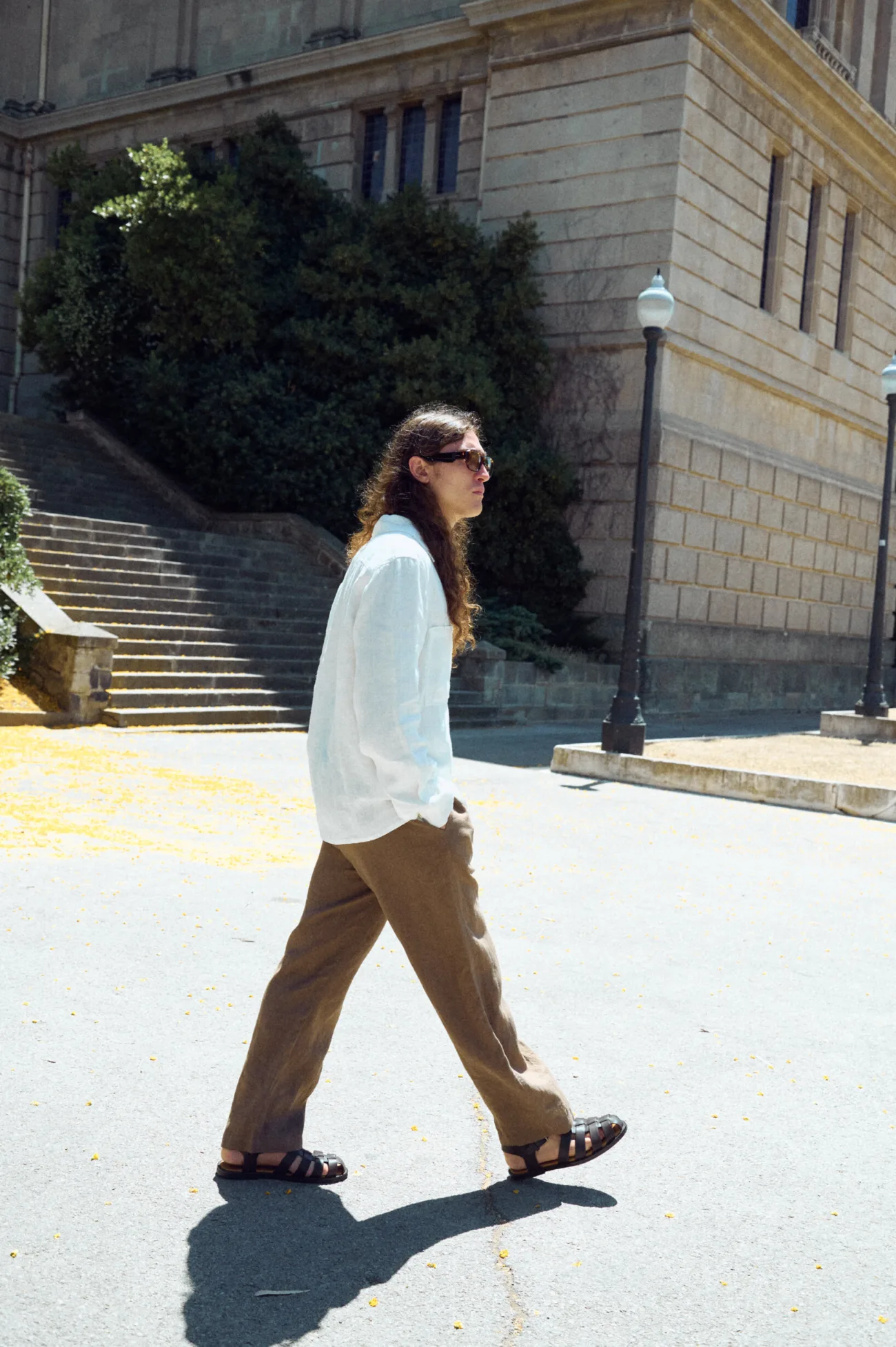 Men’s cacao brown linen trousers with a relaxed straight leg fit, shown from the side while walking with a white linen shirt