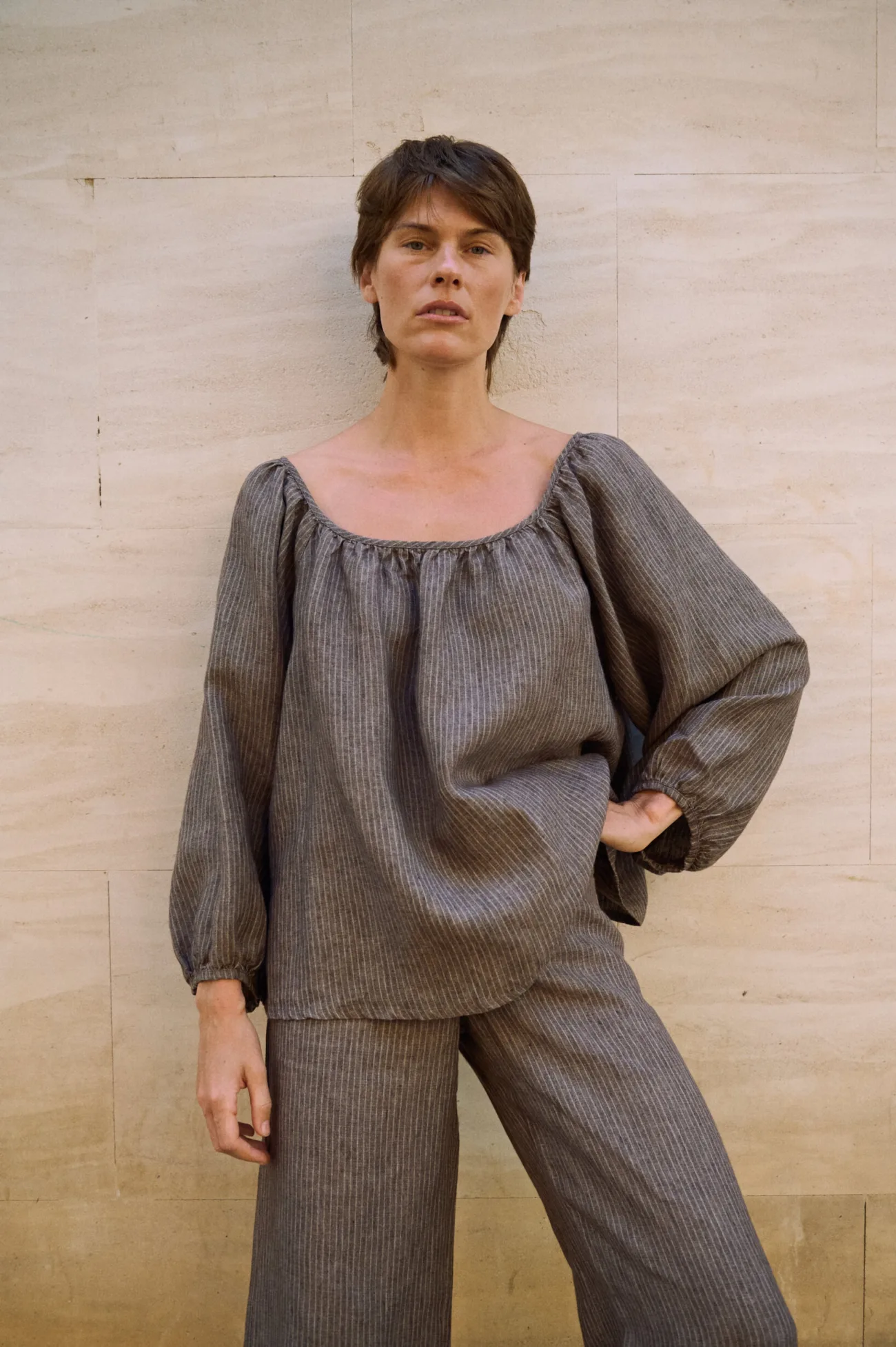 Relaxed brown striped linen blouse with a wide gathered neckline and billowy sleeves, paired with coordinating wide-leg trousers